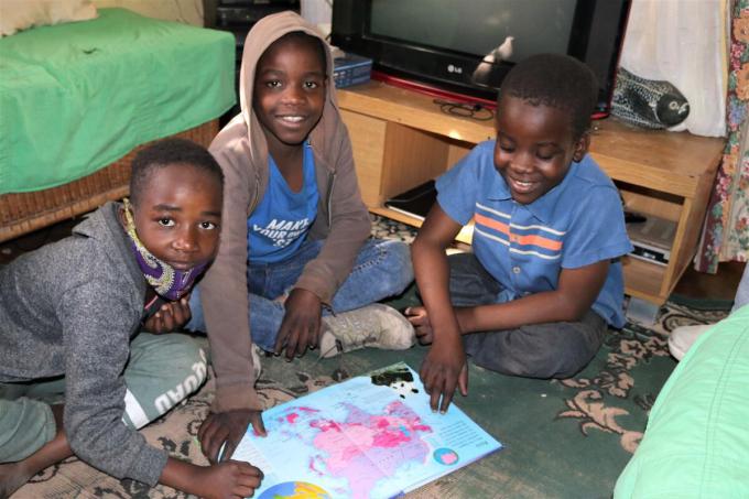 Tafadzwa reads an Atlas with his twin brother and friends