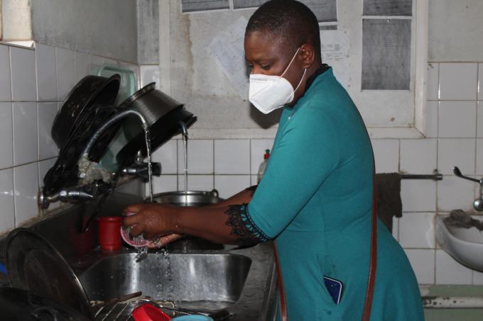 Staff member at Siakobvu Hospital washes dishes in the hospital kitchen.