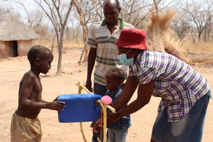 Ndakaitei helps her daughter to wash her hands