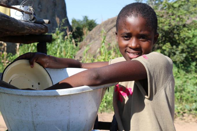 Nokwanda* 10, helps her grandmother wash dishes after their meal
